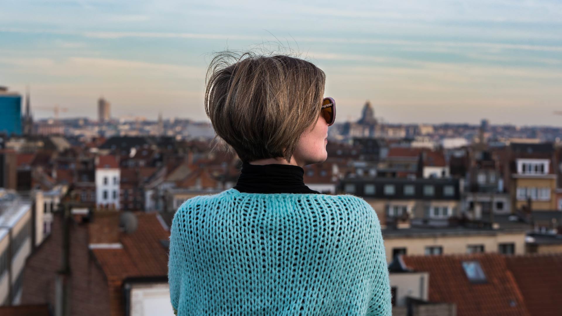 Een jonge vrouw kijkt vanop haar balkon naar Brussel
