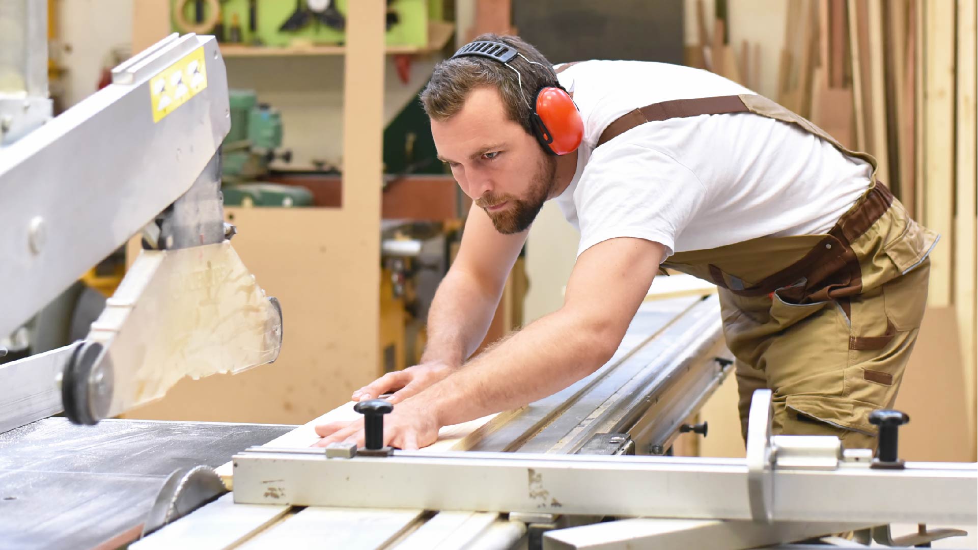 Een houtbewerker werkt in een schrijnwerkerij en zaagt hout