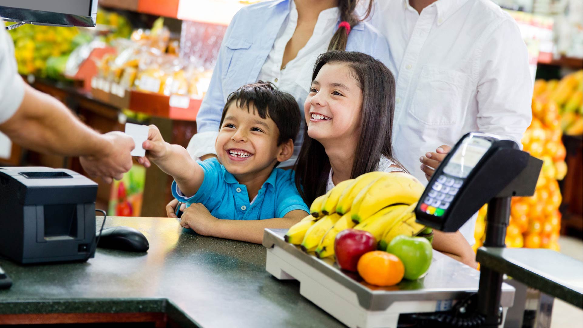 Een kind vergezeld van zijn familie betaalt aan de kassa van een supermarkt