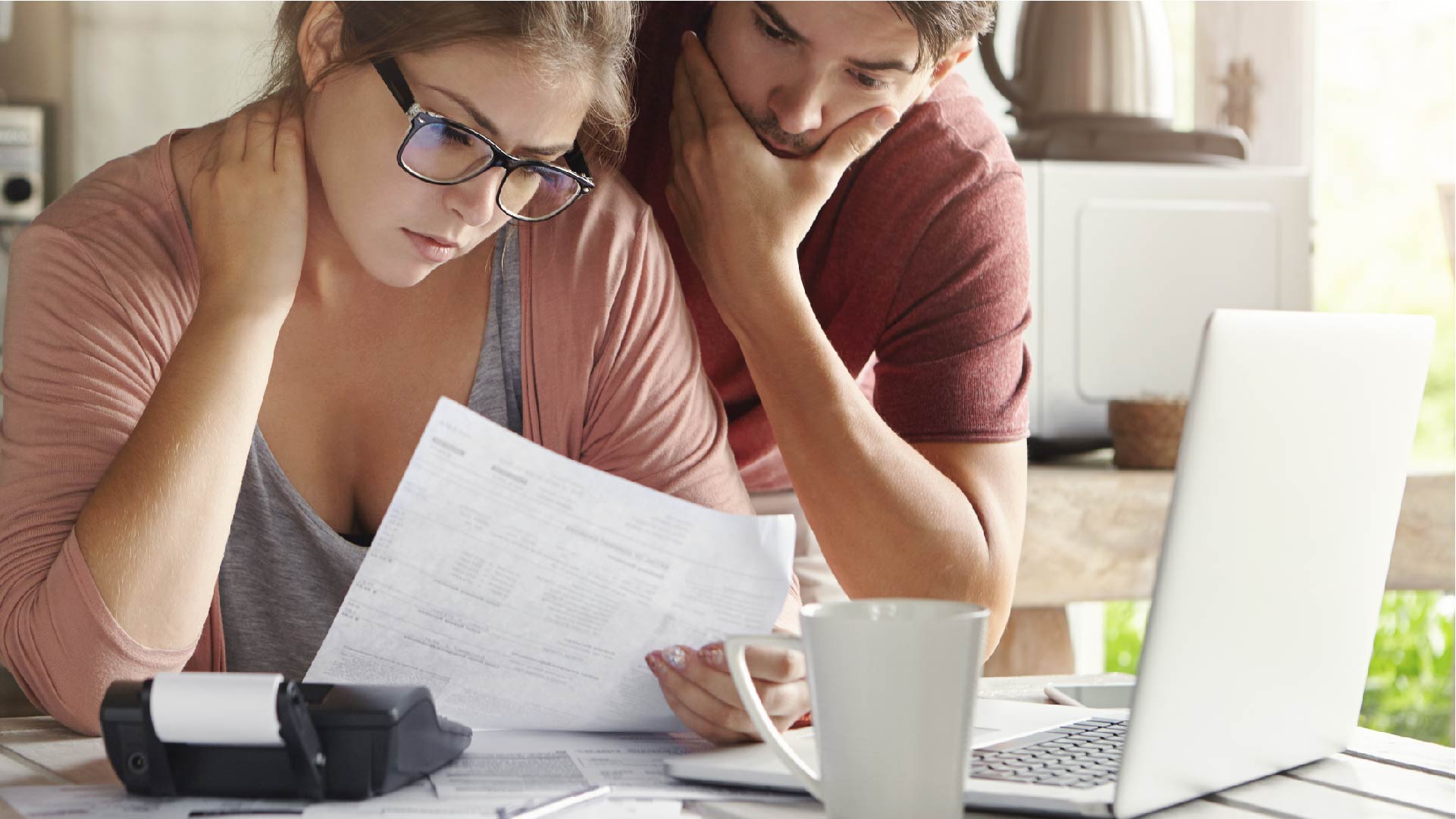 Un jeune couple regarde toutes leurs factures sur la table de leur cuisine