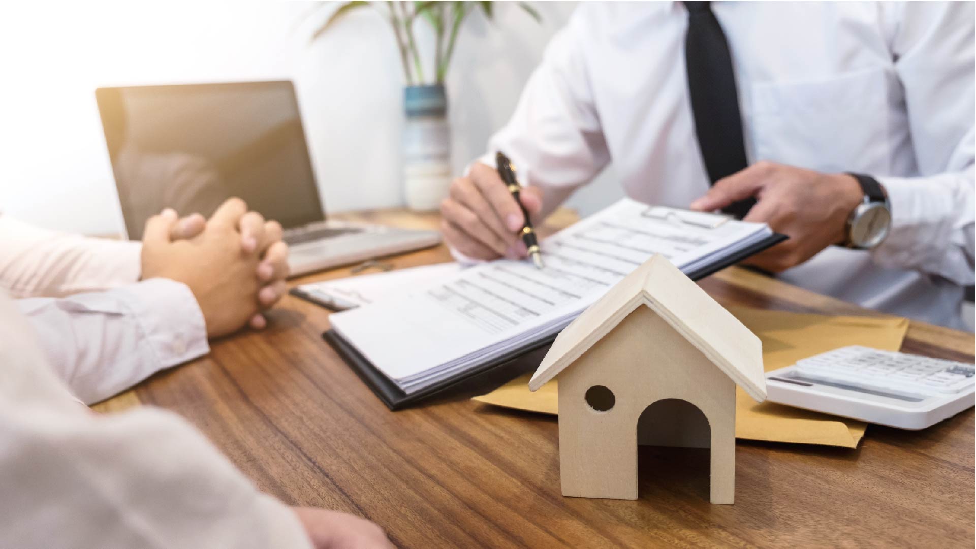 Twee personen hebben een afspraak met hun bankier en bekijken het contract dat hij hen voorlegt