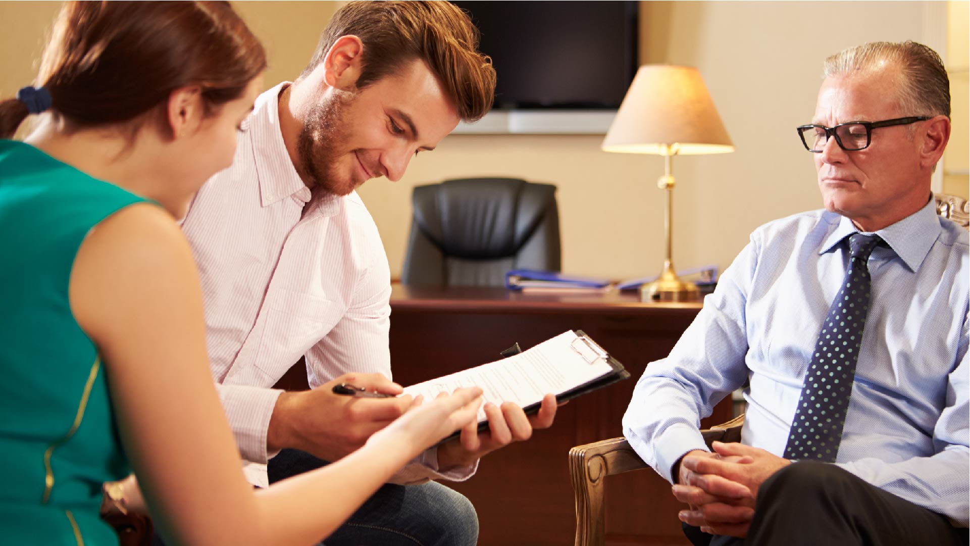 Un couple signe un contrat dans le bureau de son banquier