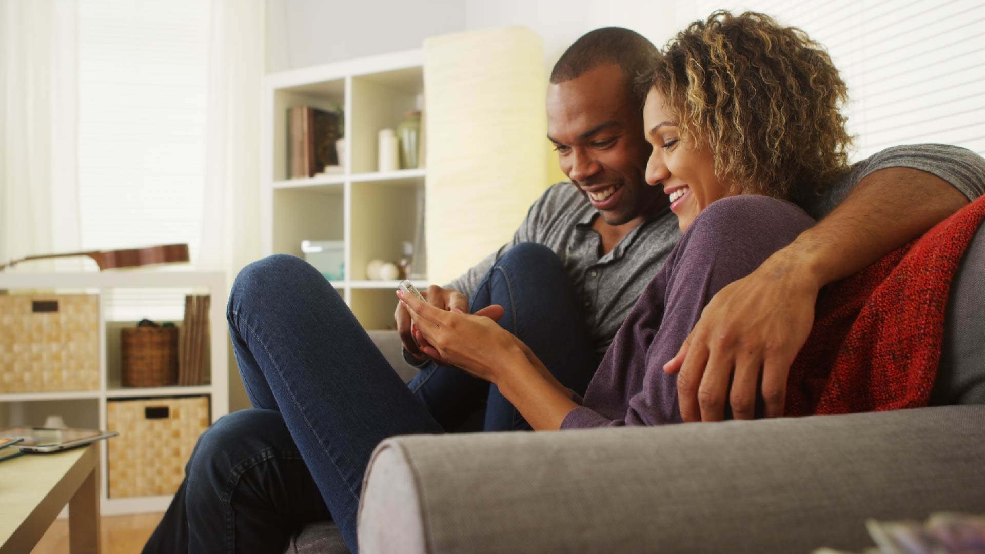 Couple assis enlacés dans le canapé et regarde leur smartphone