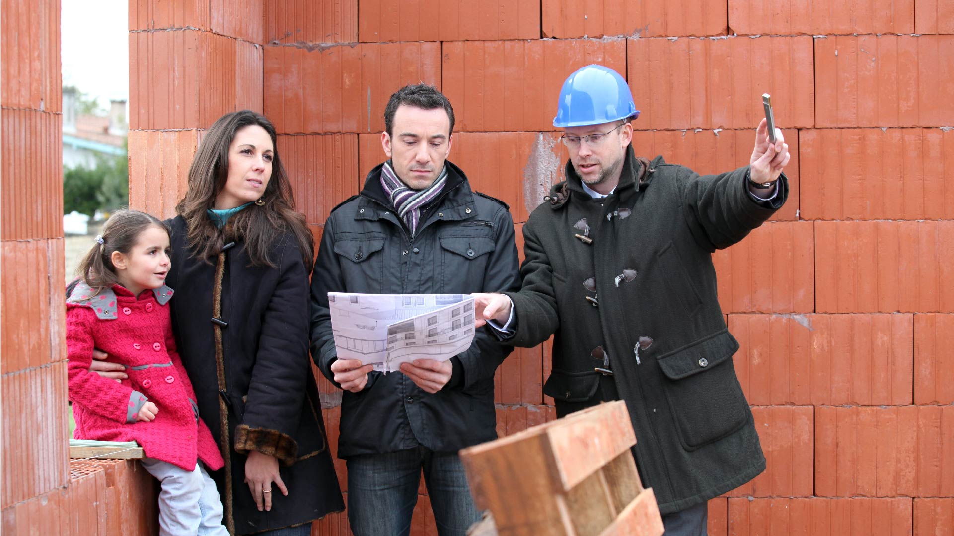 Une famille discute avec l&#039;entrepreneur sur le chantier de sa maison