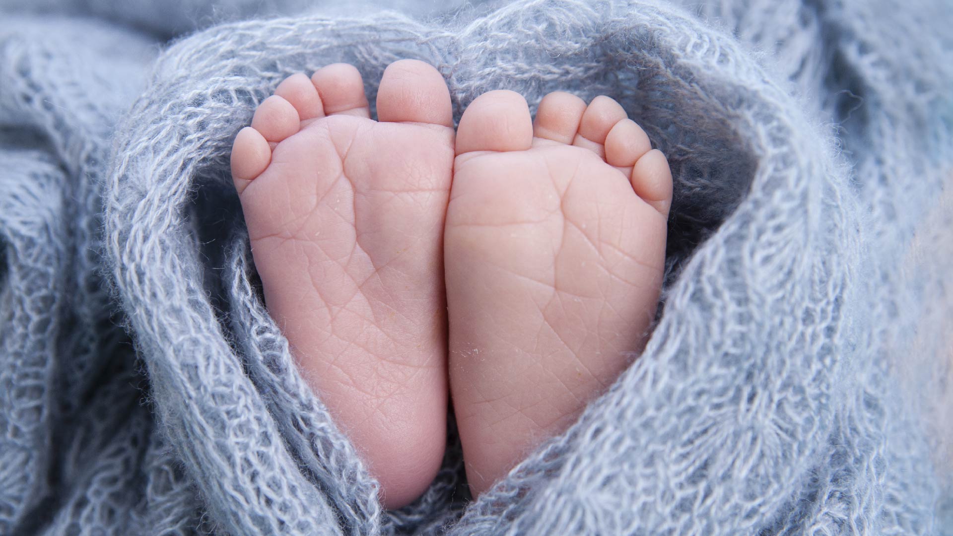 Voetjes van een pasgeborene in een grijs wollen deken gewikkeld