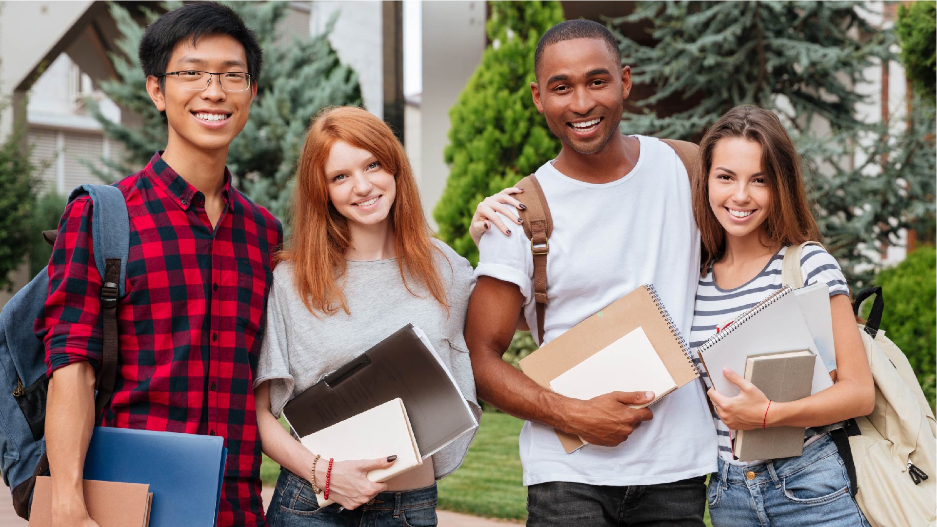 Quatre jeunes étudiants joyeux sont ensemble dehors