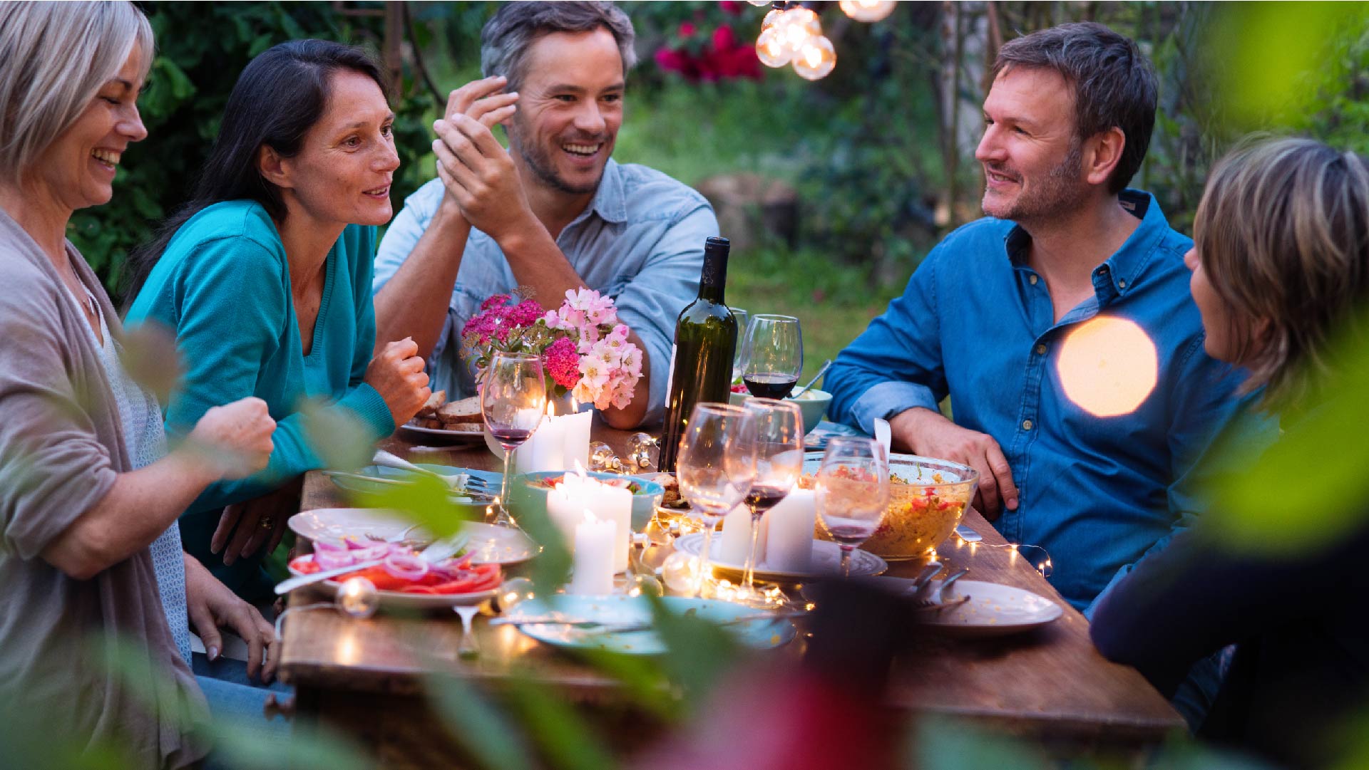 Groupe d&#039;amis réunis autour d&#039;une table dans un jardin pour partager un repas et passer un bon moment ensemble