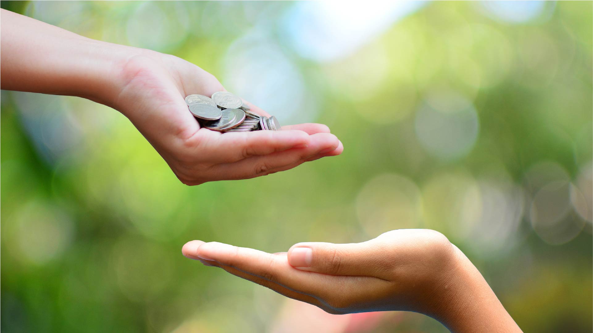 Een hand geeft muntjes aan een andere geopende hand