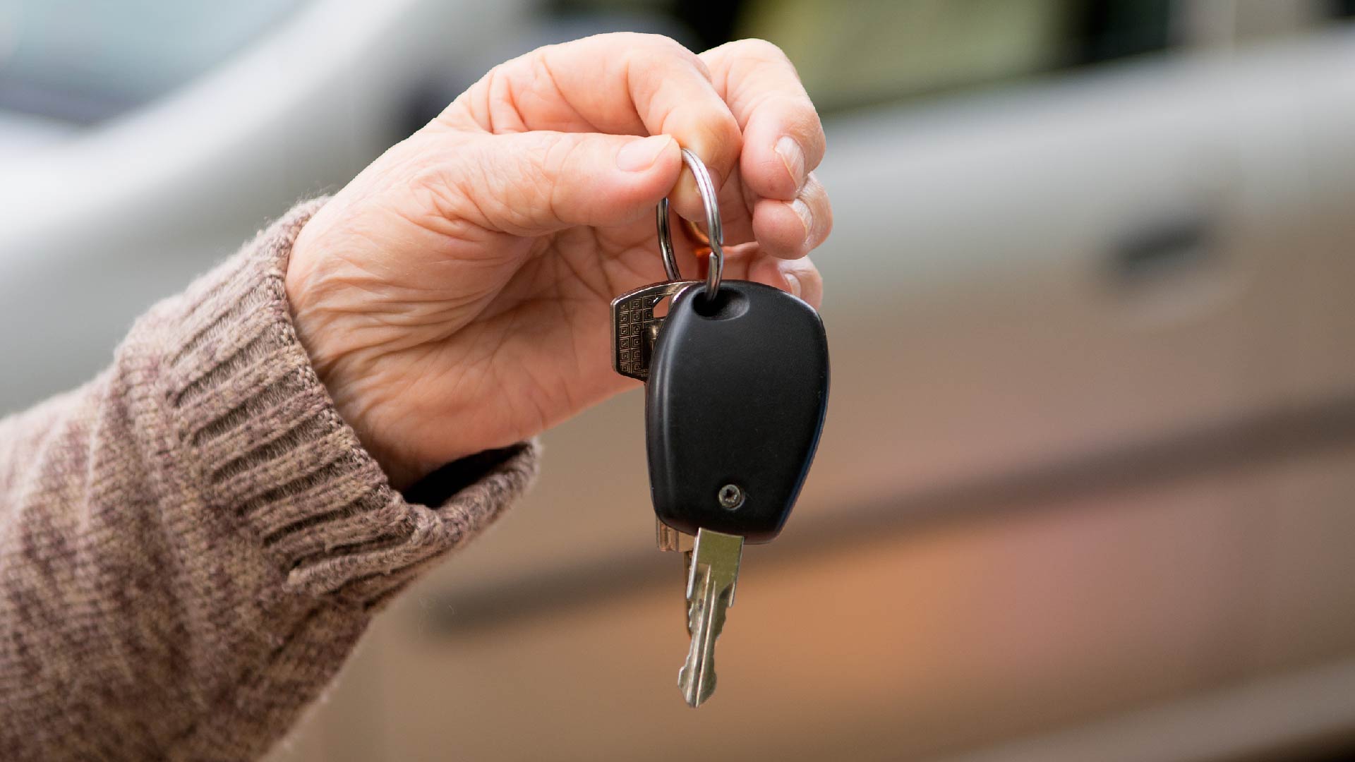 Een hand geeft autosleutels aan een andere hand