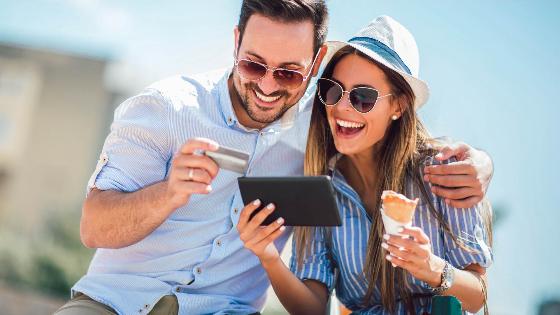 Un couple joyeux en vacances mange une glace et paie avec sa tablette