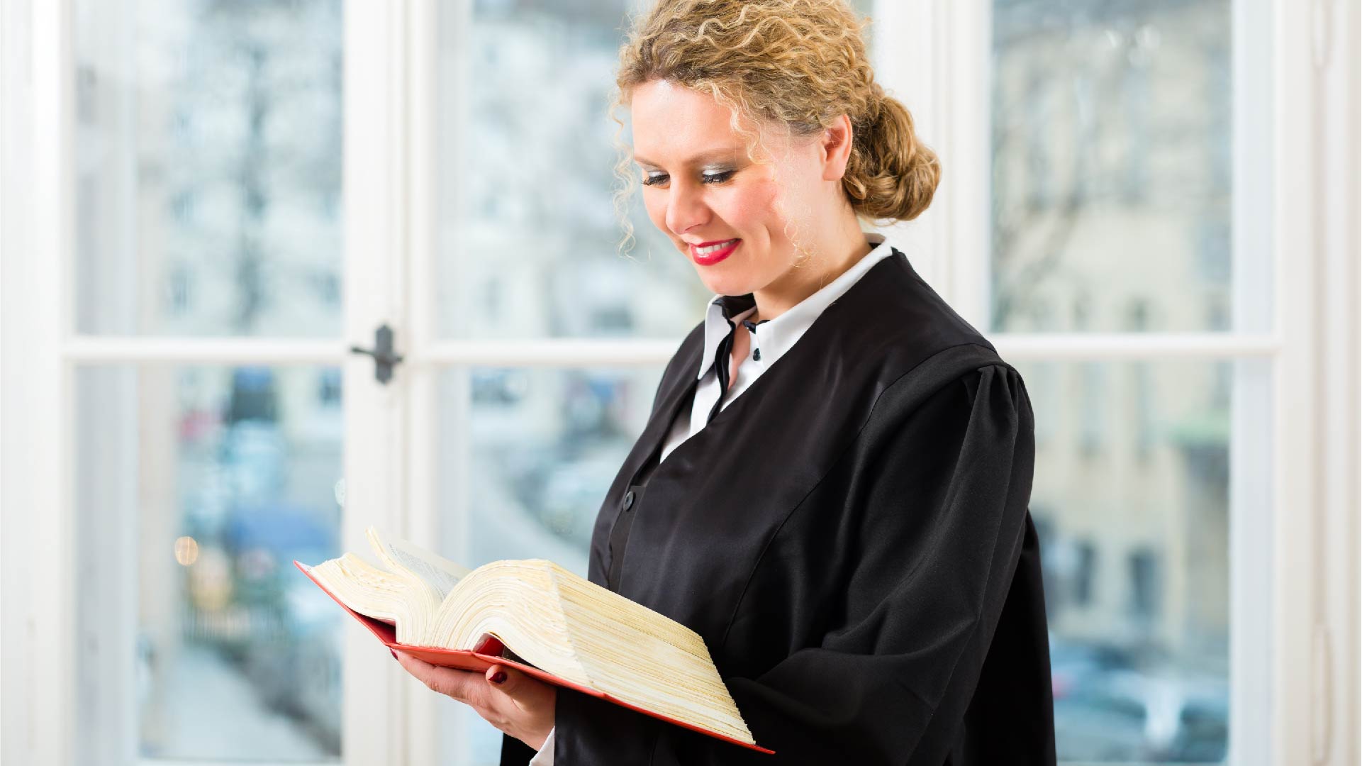 Een advocate in toga bekijkt haar wetboek
