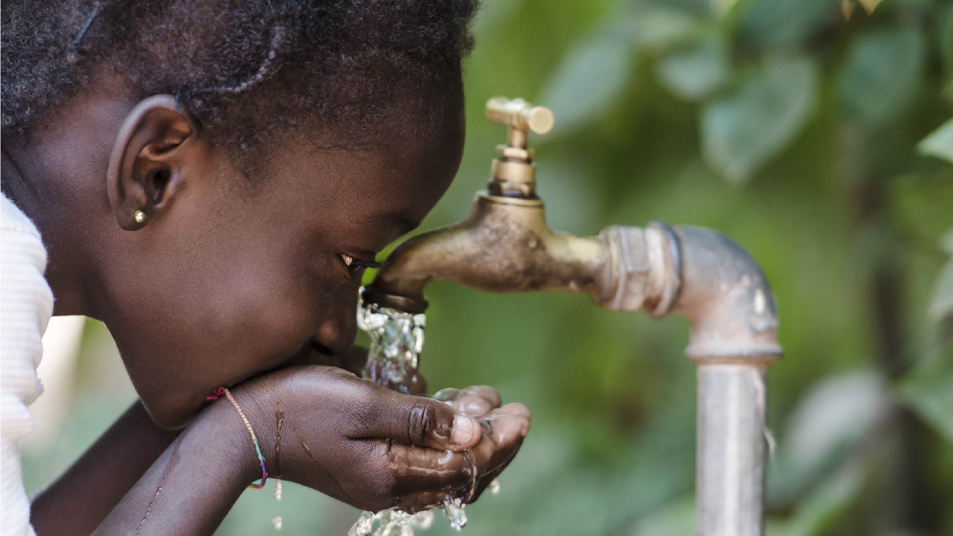 Une jeune fille boit de l&#039;eau au robinet avec ses mains
