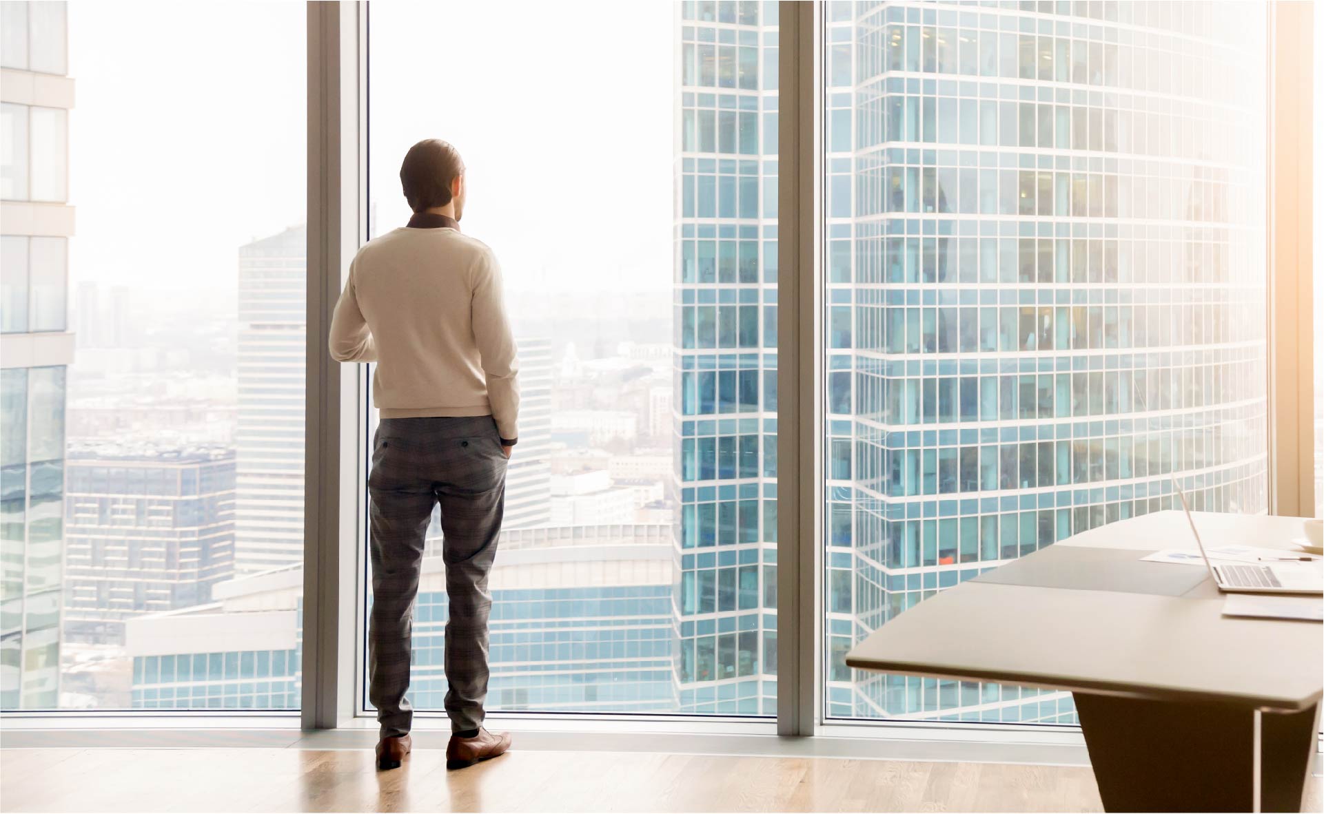 Un homme d&#039;affaire regarde au loin par la fenêtre de son bureau