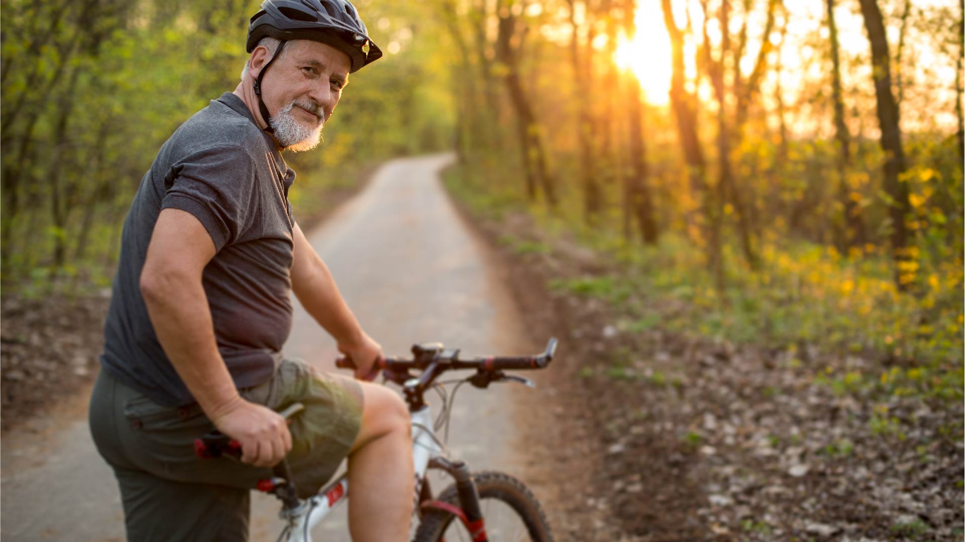 Een rijpere man rijdt met de fiets in het bos