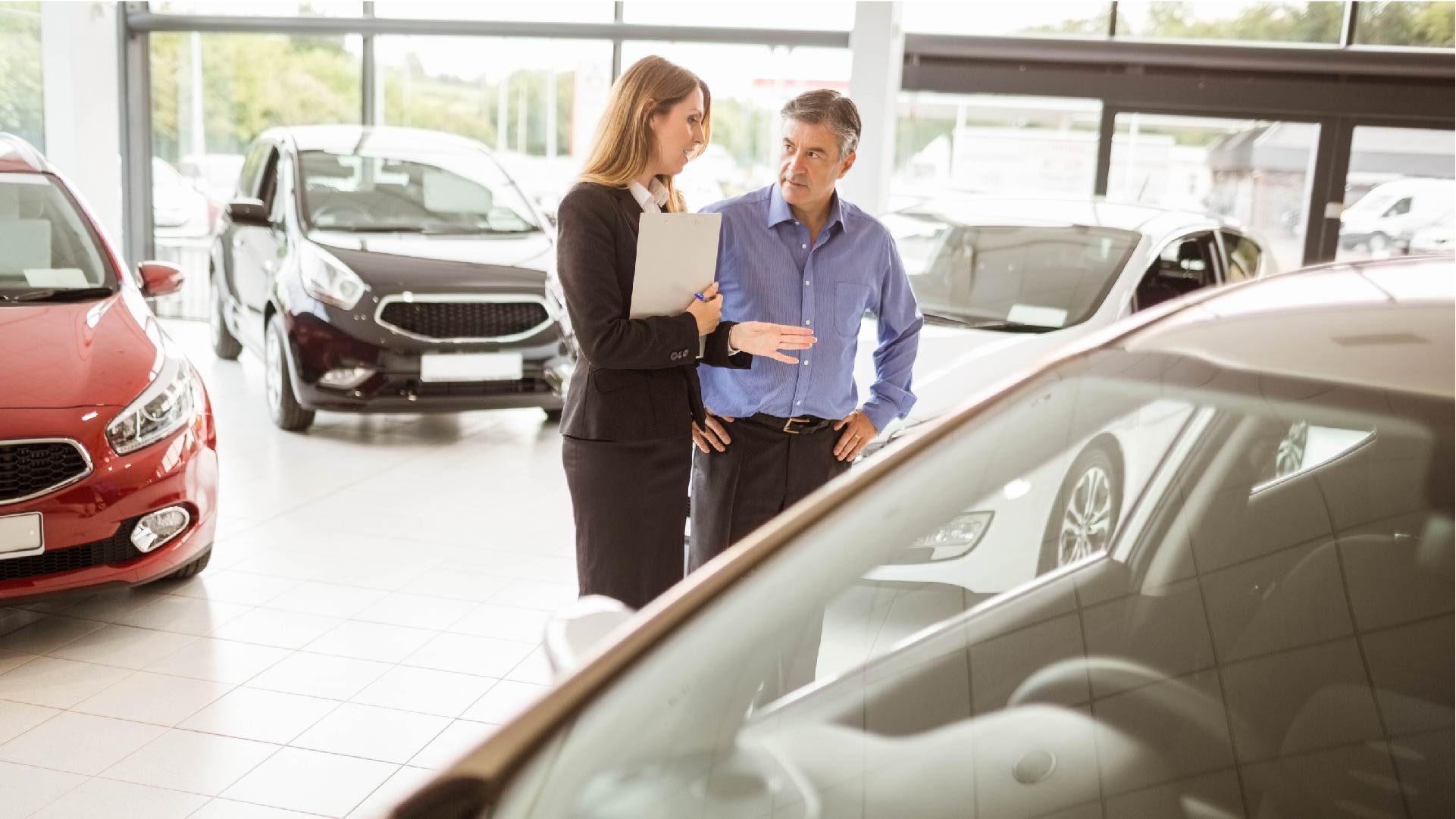 Een oudere man vraagt informatie voor de aankoop van een nieuwe wagen in een showroom