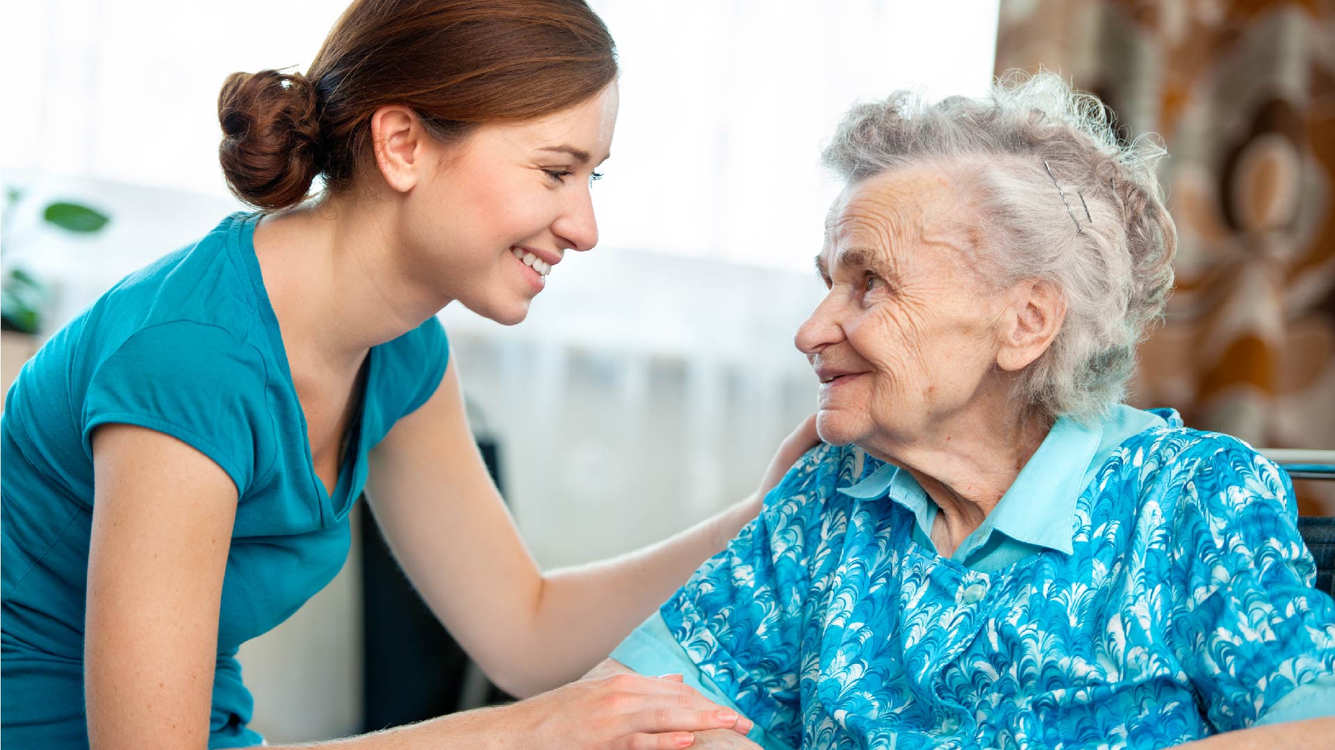 Een zorgkundige en een heel oude dame glimlachen naar elkaar