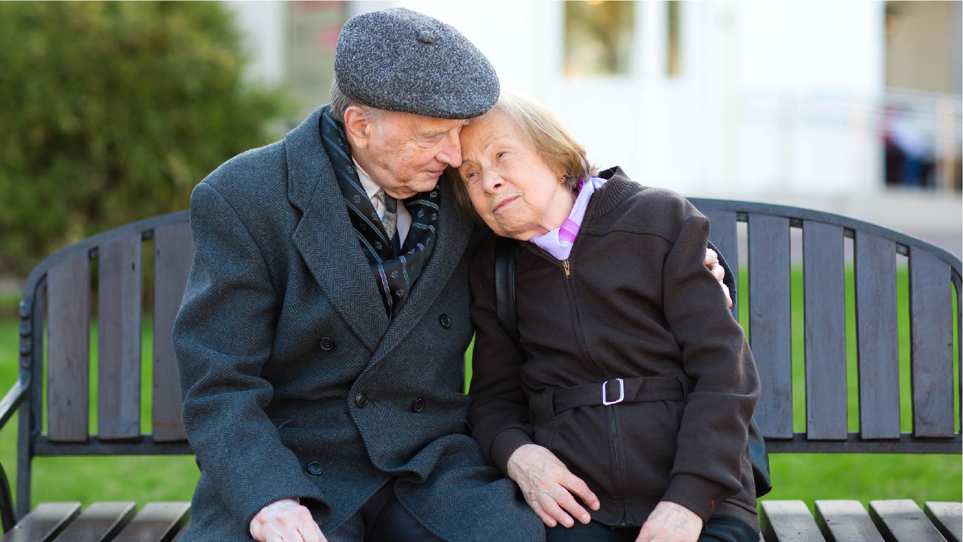 Un couple âgé est assis sur un banc et s&#039;enlace