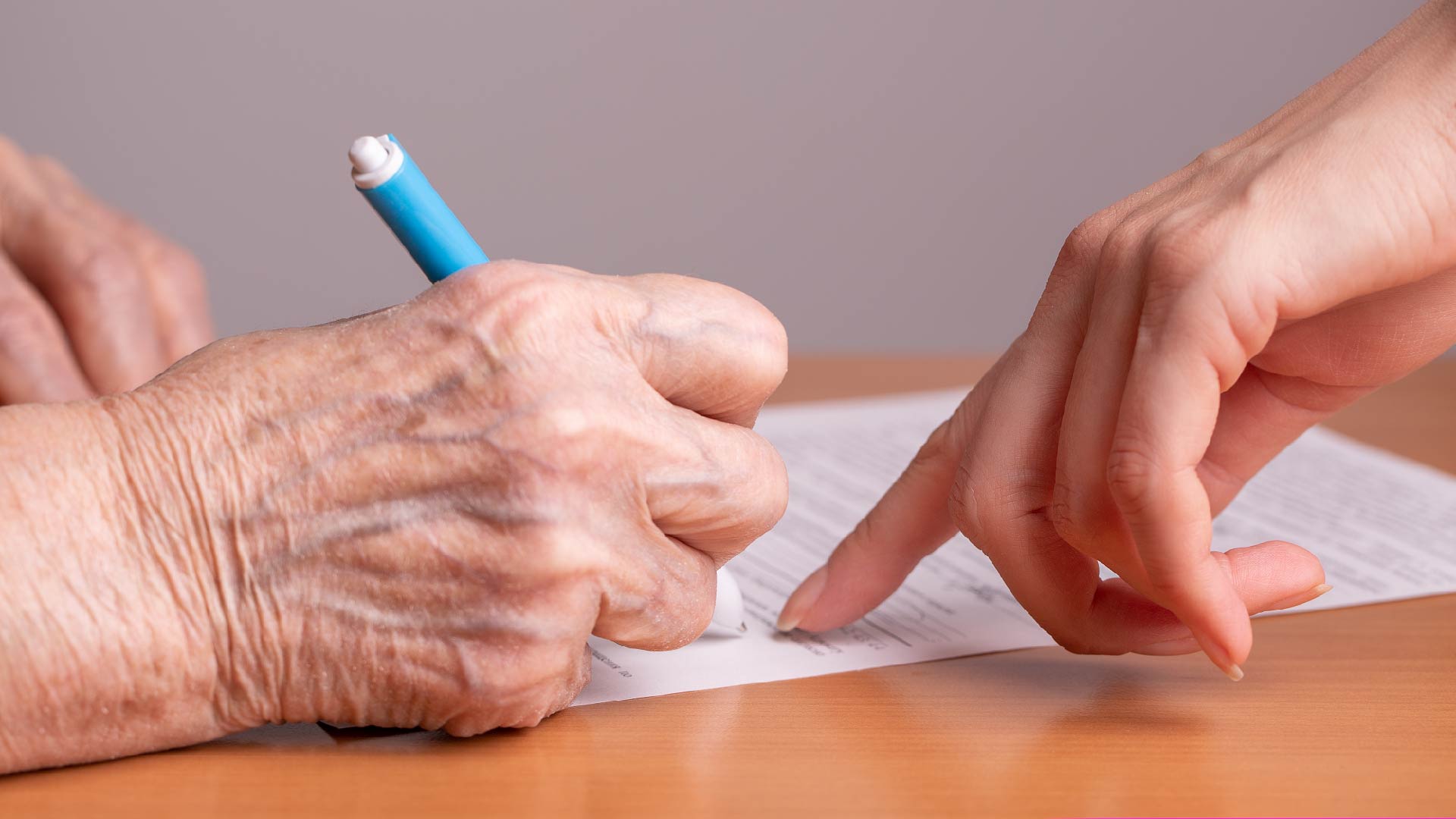 Une main âgée signe un contrat