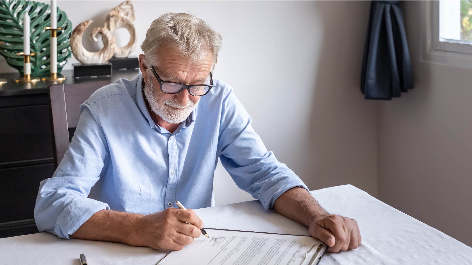 Een oude man zit aan tafel om zijn testament te schrijven