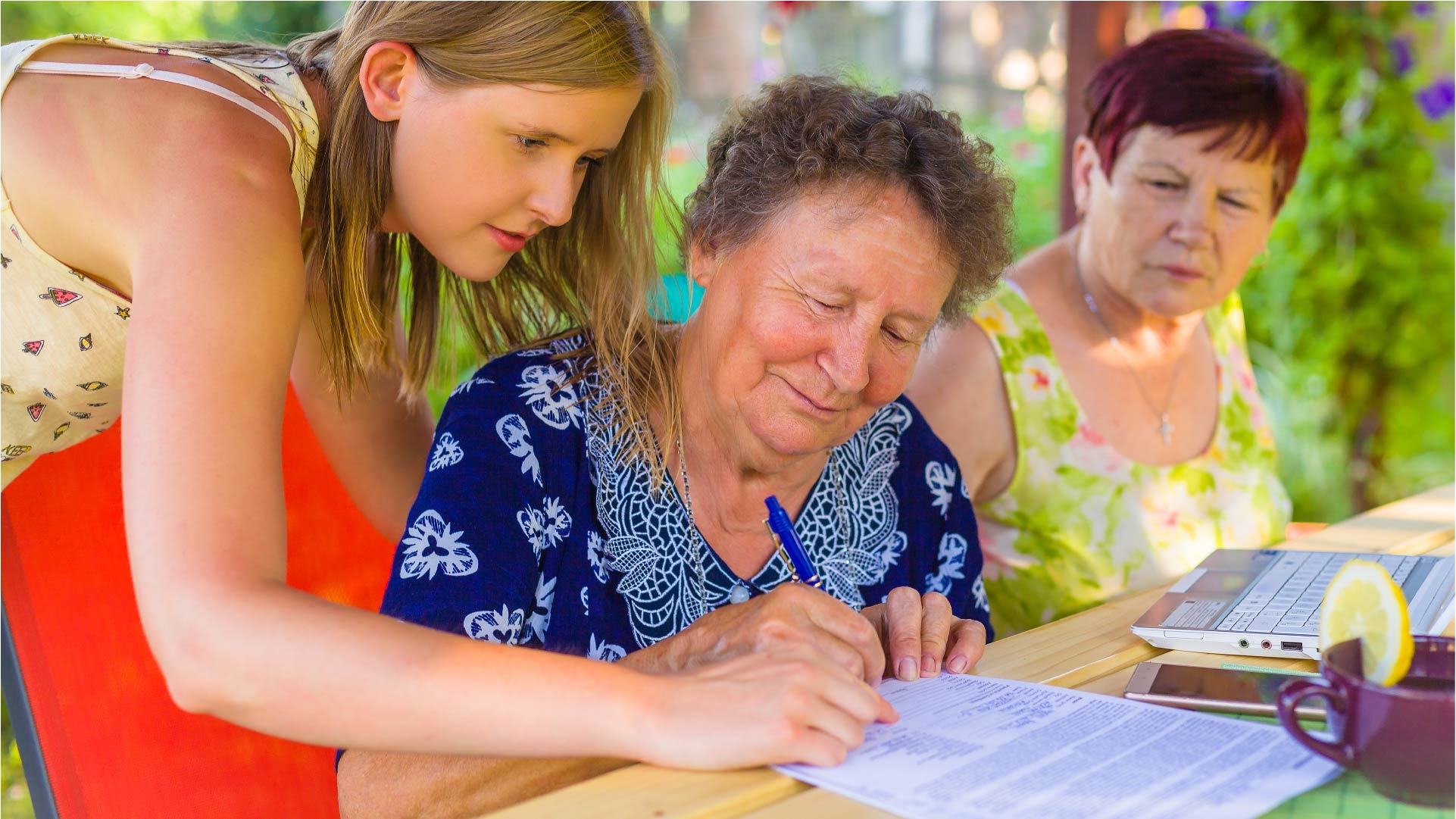 Une dame âgée signe son testament aux côtés de sa petite-fille