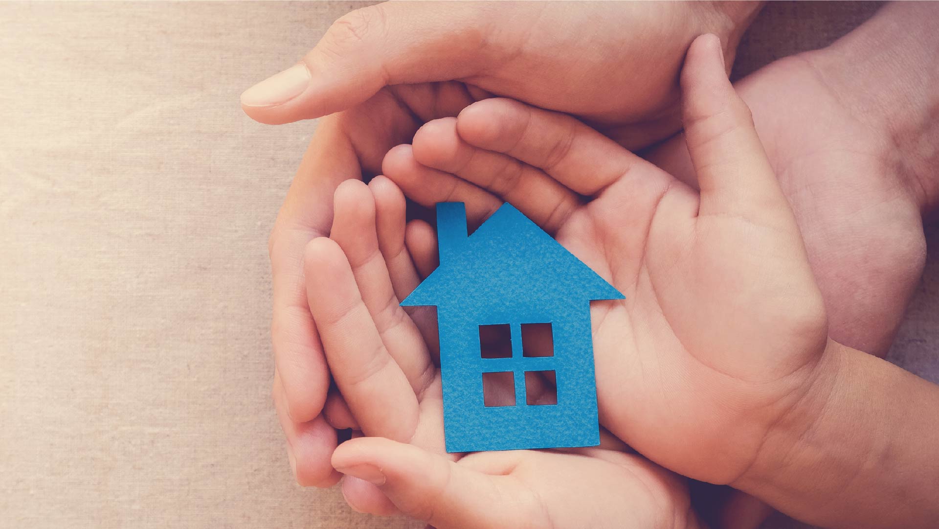 Des mains d&#039;enfant superposées à des mains d&#039;adultes et tiennent une maison en papier