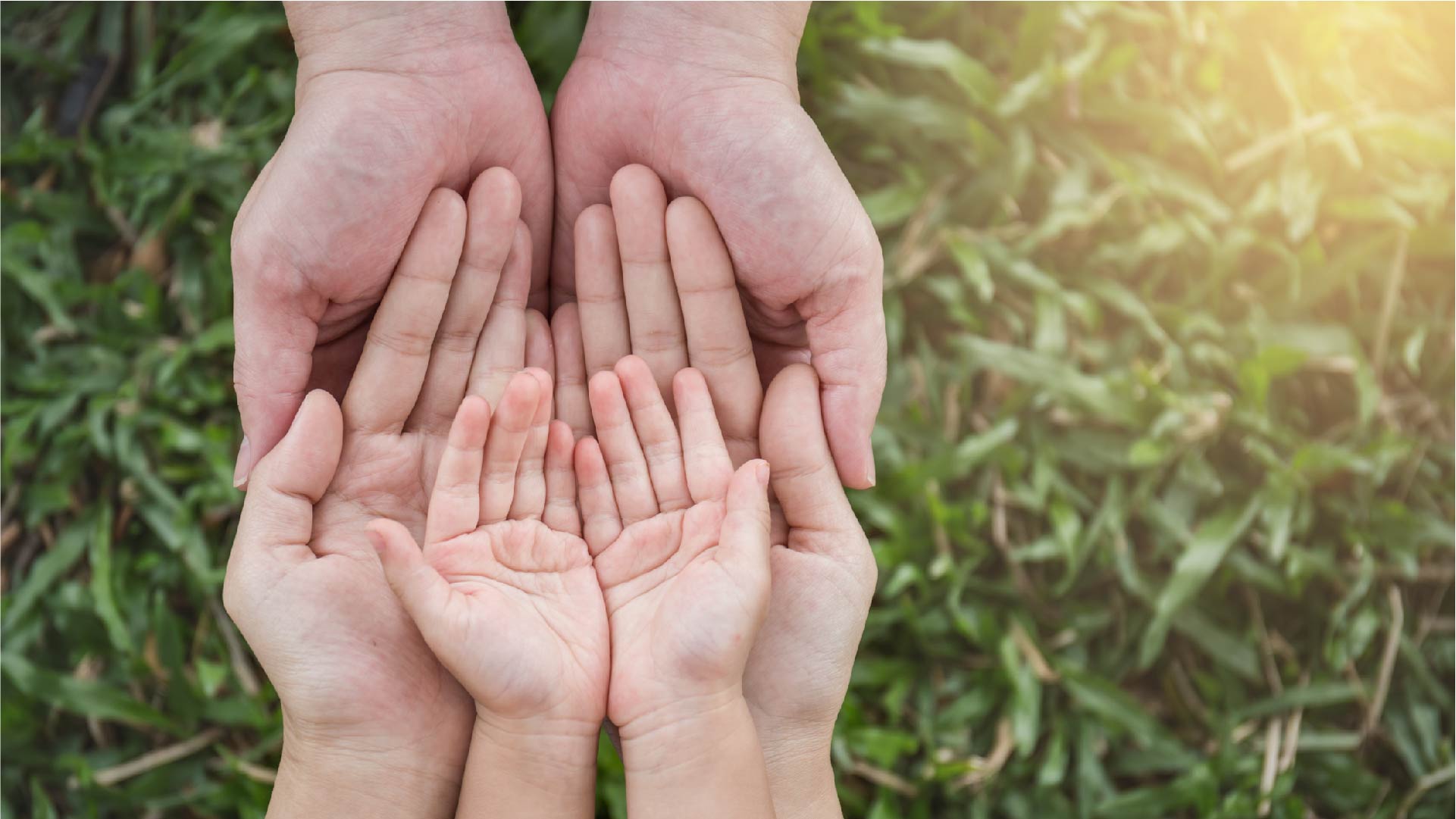 De handen van een kind, een vrouw en een man zijn op elkaar gestapeld met open handpalmen