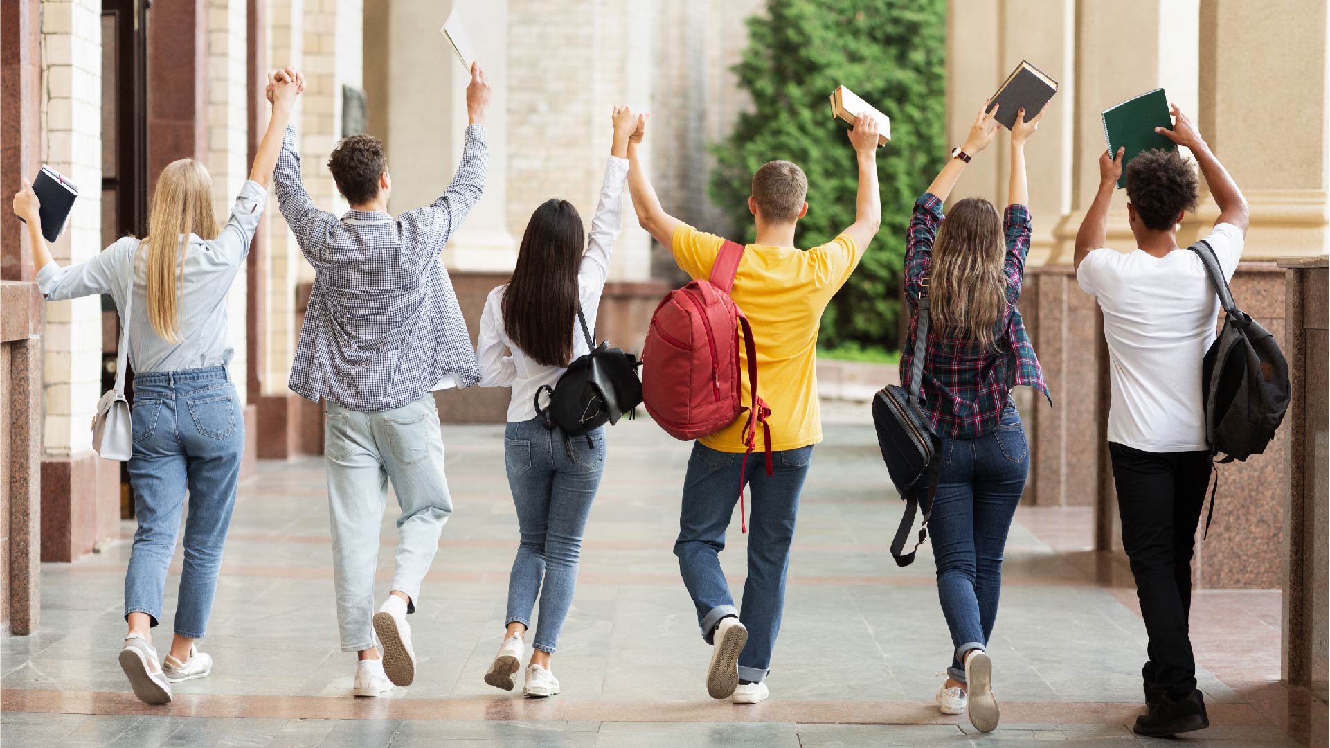 Een groepje van 6 jongeren steekt opgelucht zijn boeken in de lucht