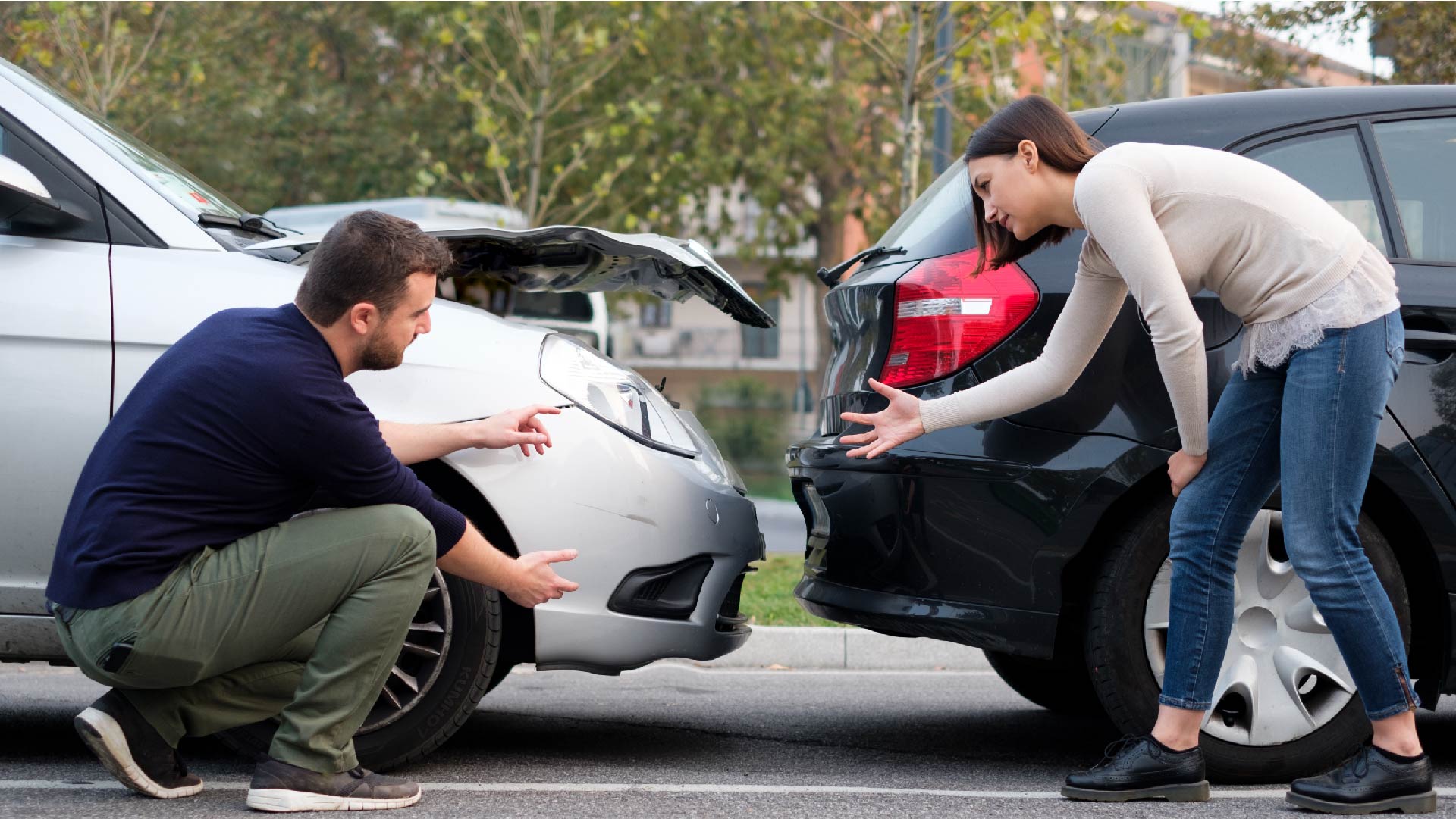 Een man en een vrouw kijken naar de schade aan hun auto&#039;s na een ongeval