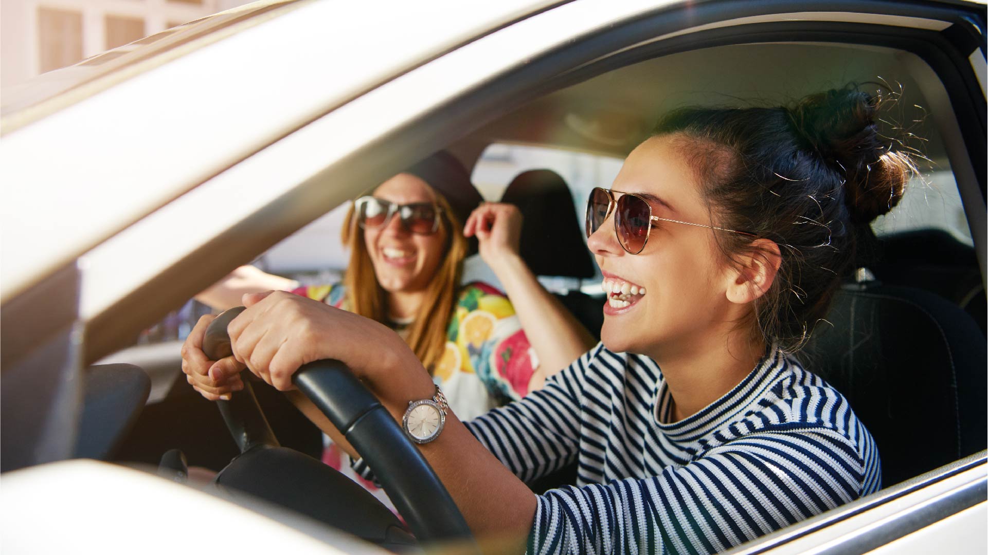 Een jonge vrouwelijke chauffeur zit samen met haar vriendin in de auto