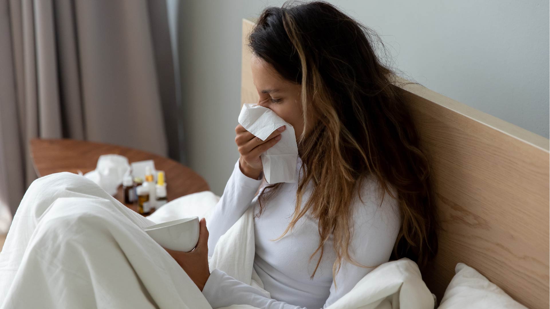 Une femme malade dans son lit se mouche