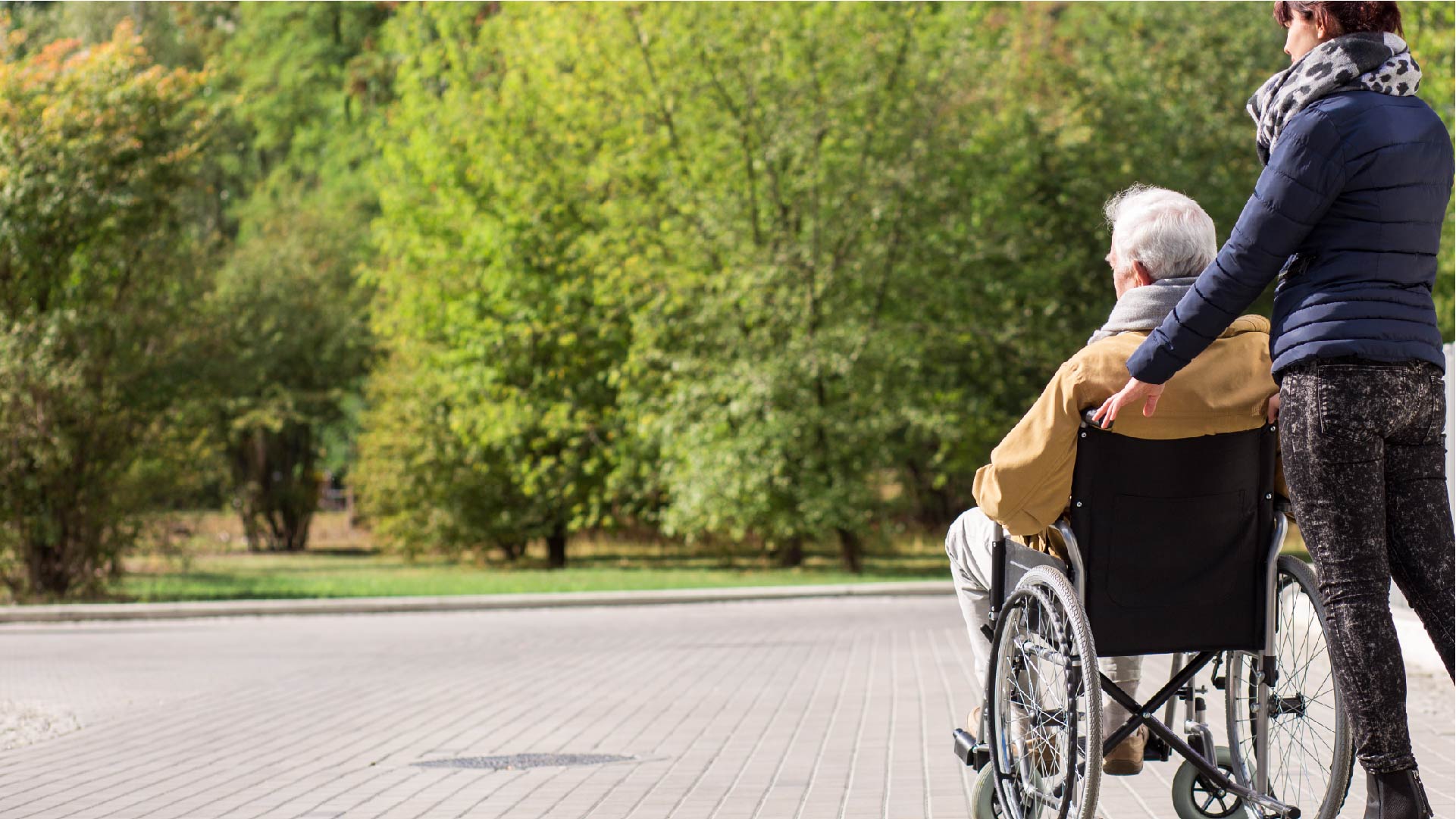 Une femme pousse une personne âgée en chaise roulante