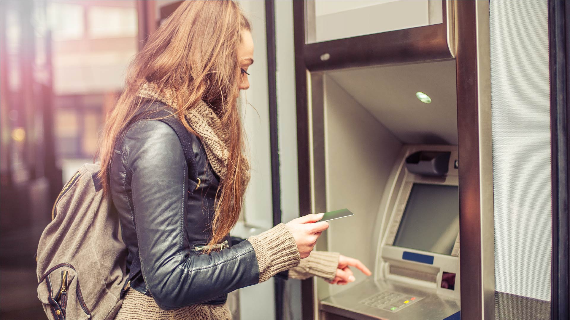 Une jeune femme retire de l&#039;argent au guichet automatique