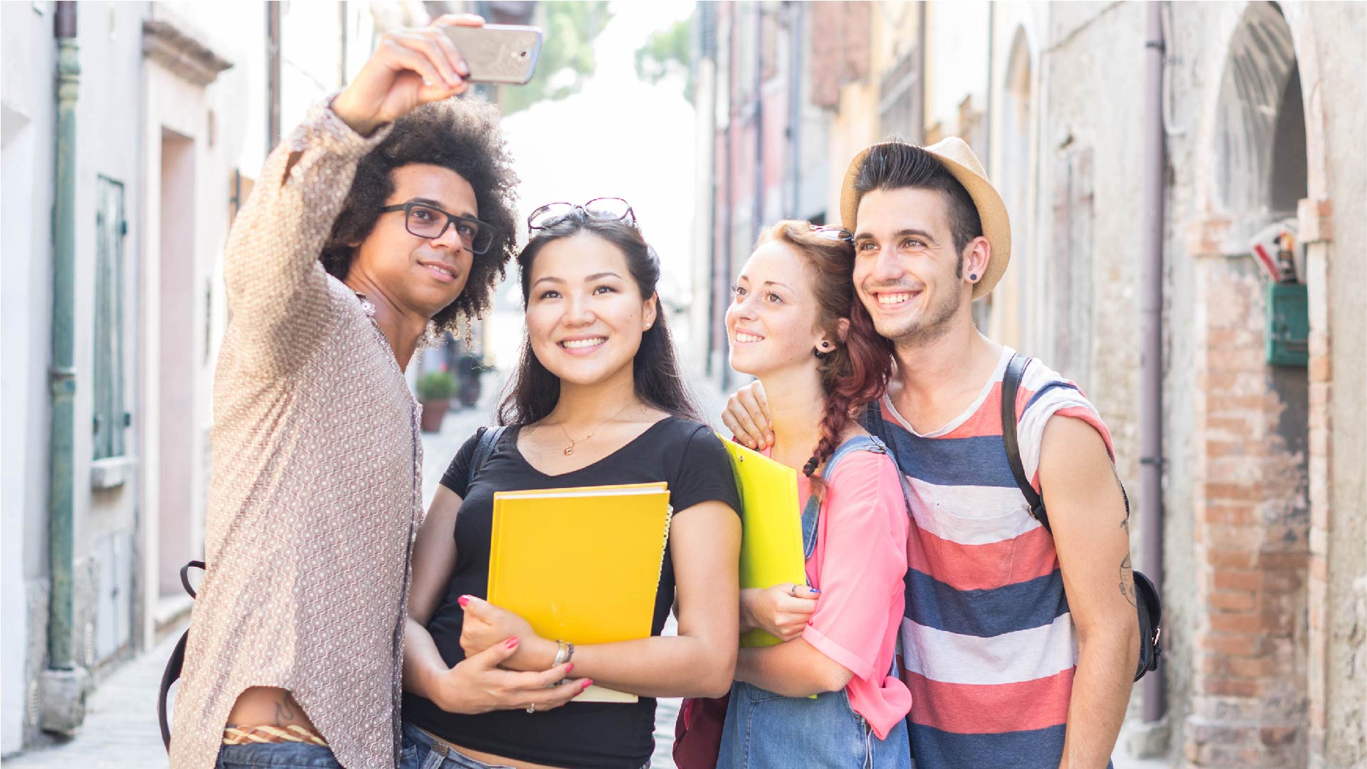Vier jongeren met hun schriften nemen een selfie in een straat in het buitenland