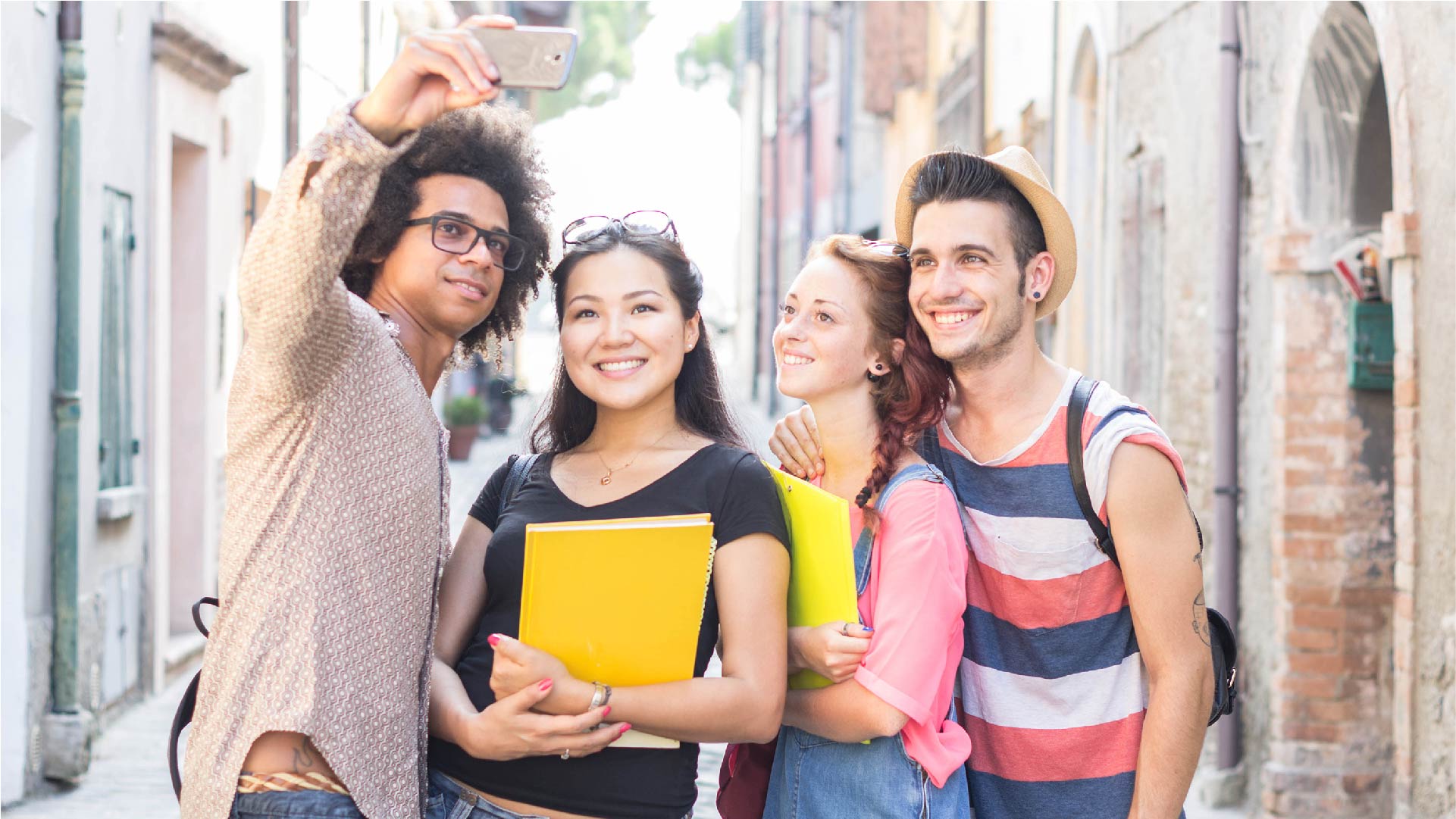 Un groupe de 4 étudiants couchés dans l&#039;herbe et qui étudient en plein air