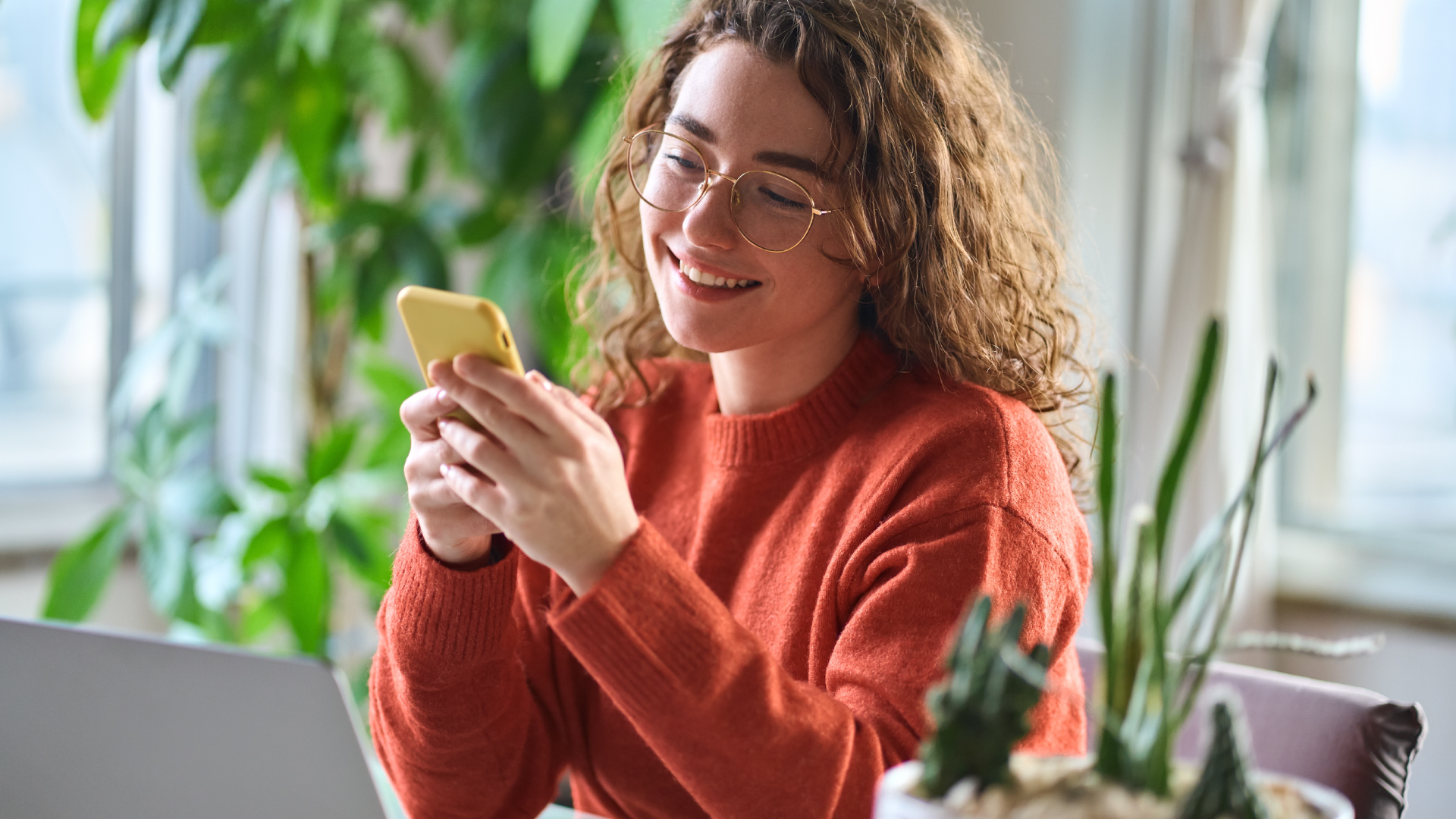 Een jonge vrouw glimlacht terwijl ze naar haar smartphone kijkt