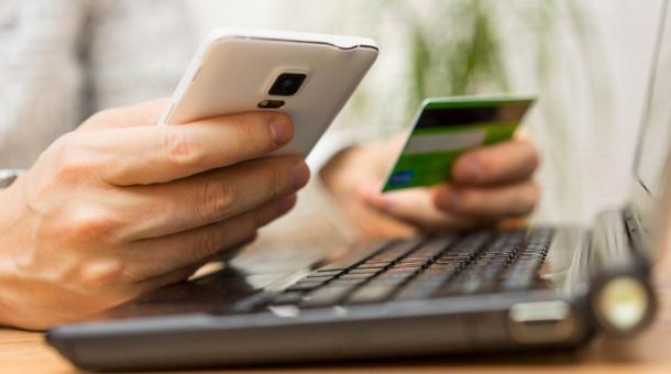 Een persoon houdt zijn smartphone in één hand en zijn bankkaart in de andere
