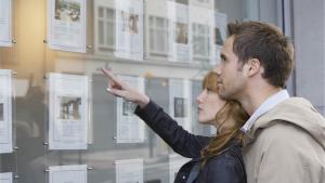 Un couple regarde les annonces  d&#039;une agence immobilière