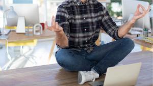 Een rustige man doet yoga achter zijn bureau