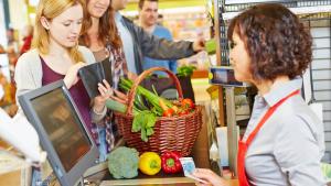 Een jonge vrouw haalt haar portefeuille boven om te betalen aan de kassa van de supermarkt