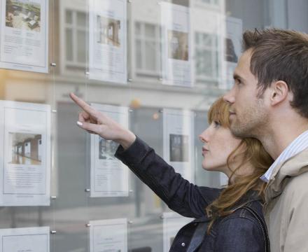 Un couple regarde les annonces  d&#039;une agence immobilière