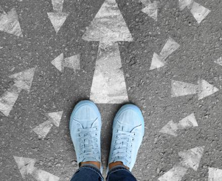 Des pieds sont posés sur la rue au milieu de flèches blanches