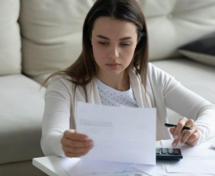 Une jeune femme perdue à la lecture de sa fiche de salaire
