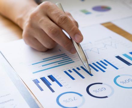 Une main tient un bic et montre des graphiques