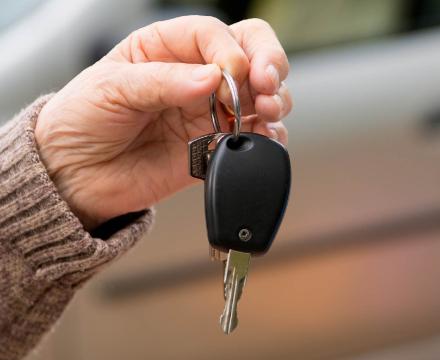 Een hand geeft autosleutels aan een andere hand