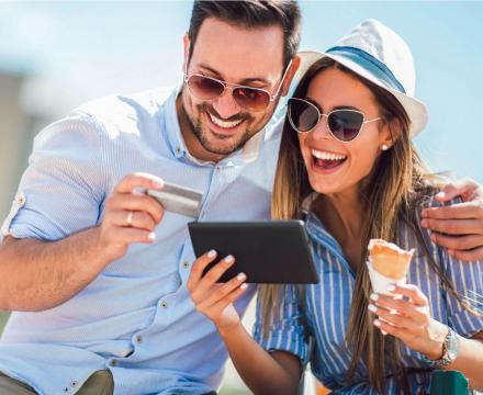Een vrolijk koppel op vakantie eet een ijsje en betaalt met hun tablet