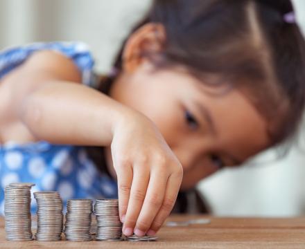 Une petite fille fait des piles de pièces de monnaie