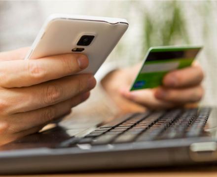 Een persoon houdt zijn smartphone in één hand en zijn bankkaart in de andere