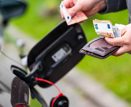 Een man houdt zijn geld klaar om de benzine van zijn auto te betalen