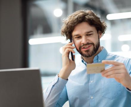 Een man is aan de telefoon en kijkt naar zijn bankkaart