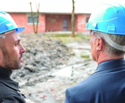 Deux hommes regardent une maison en construction
